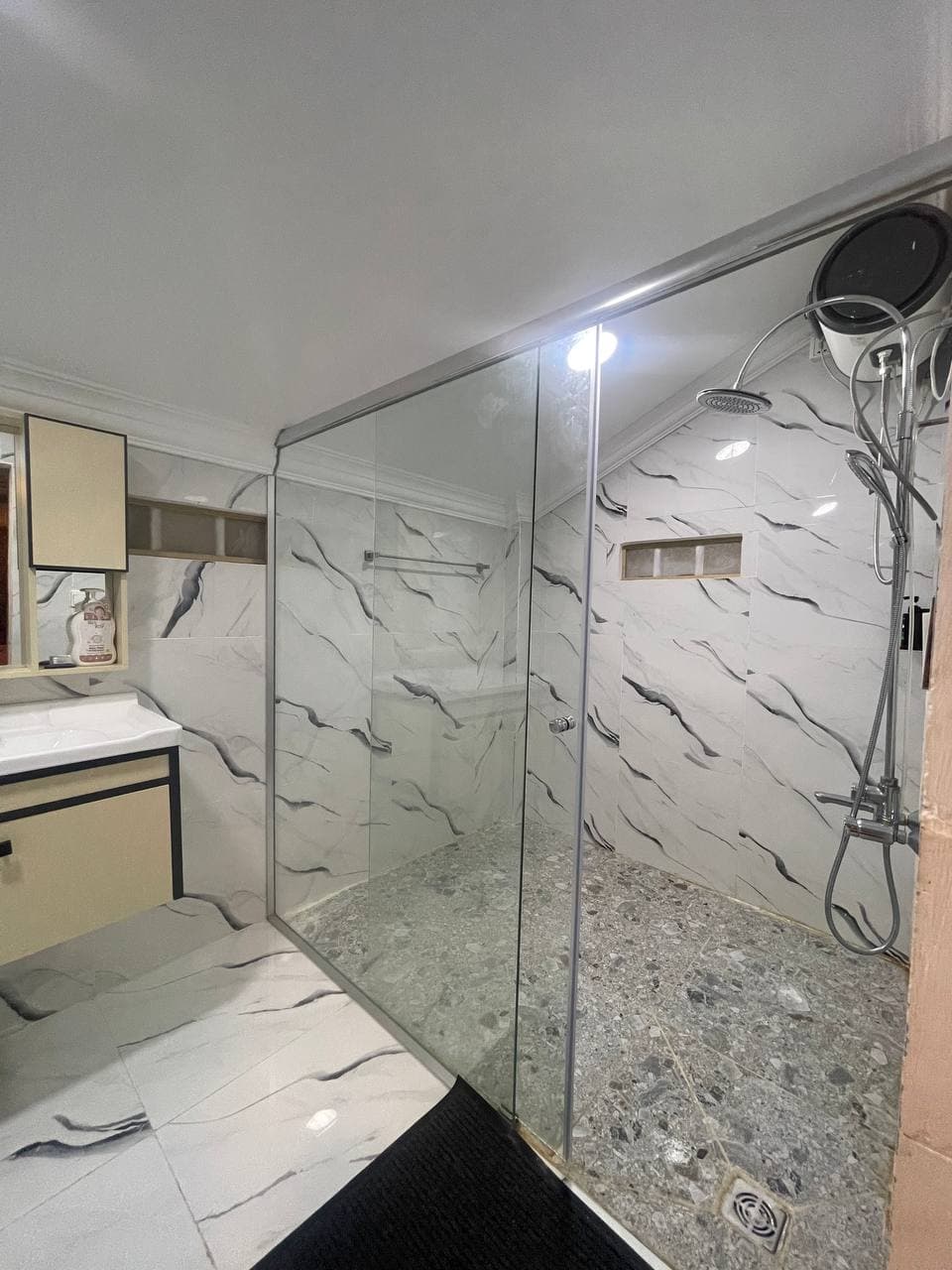 Modern bathroom with large glass shower and marble walls