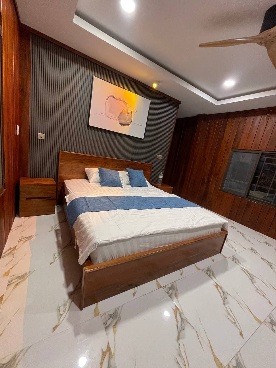 Queen bed with rich wood paneling and blue accents